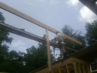 Carpenter setting a ridge beam over a new addition frame — Ice Dam Removal by Roofing Brothers in Ashley