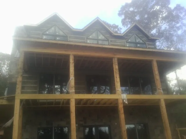 Dormers and porch framing on a large log home under construction — Roof Coating work by our crew in Ashley